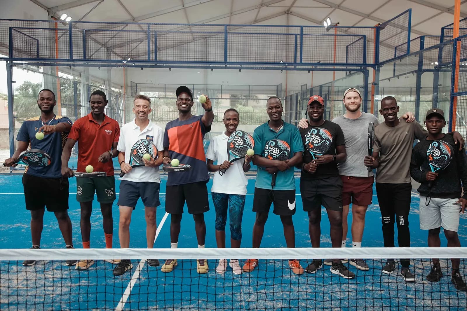 Sekelompok pemain padel berfoto bersama di depan net setelah bermain